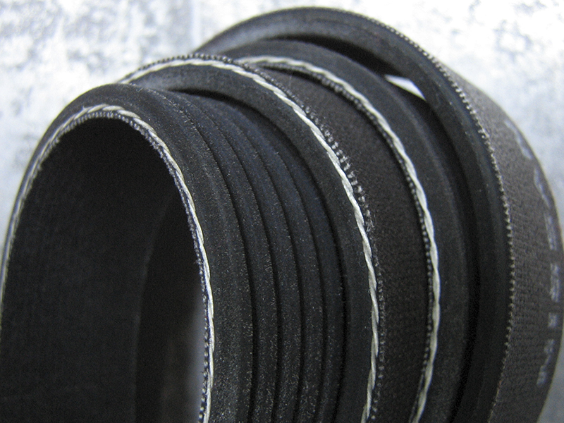 This serpentine belt has a reinforced backing seen in the white threads, and it has additional material for powering pulleys using the nonribbed side.