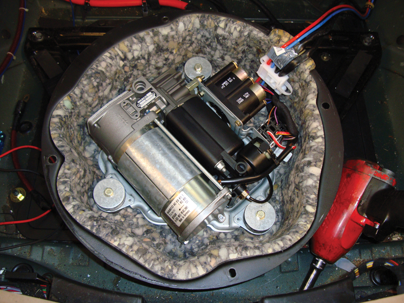 The air compressor assembly is mounted underneath the spare tire. This is the EHC I system, so what you are seeing here is the compressor, compressor relay, and the two air spring solenoids. You can electrically test everything from here. EHC II is a little more involved.