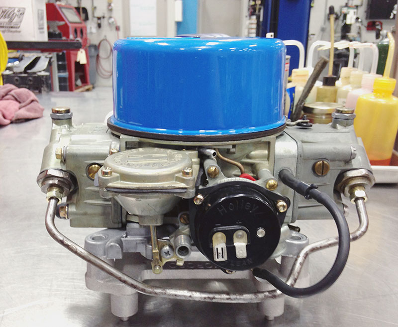 This is actually a stock carb off a 1969 Ford, and it shows you something interesting. Not only does it use a left inlet with a transfer pipe down the right side, it also uses both exhaust manifold heat and an electric choke. Like our later model Holley carb shown elsewhere in this feature, it also uses a pull-down piston located under the choke spring cap to qualify the choke once the engine starts. The takeaway here is that there are lots of ways to skin a cat and you can find a lot of examples of just how that skinning happens if you end up working on older vehicles. Basics are basics, though — remember to note when and where your performance falls off and then work on those components that are in play during that specific period of engine warm-up.